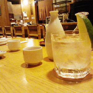 A glass of sake on the rocks with some Tokkuri carafes at an Izakaya setting.