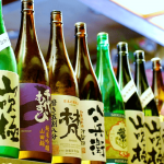 Colorful bottles of sake lined up, each facing forward with its own unique labels.