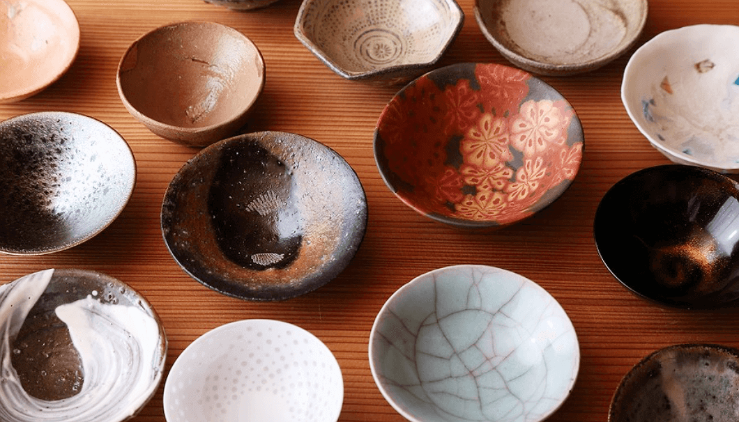 Variety of colorful "ochoko" sipping cups on a wooden surface.